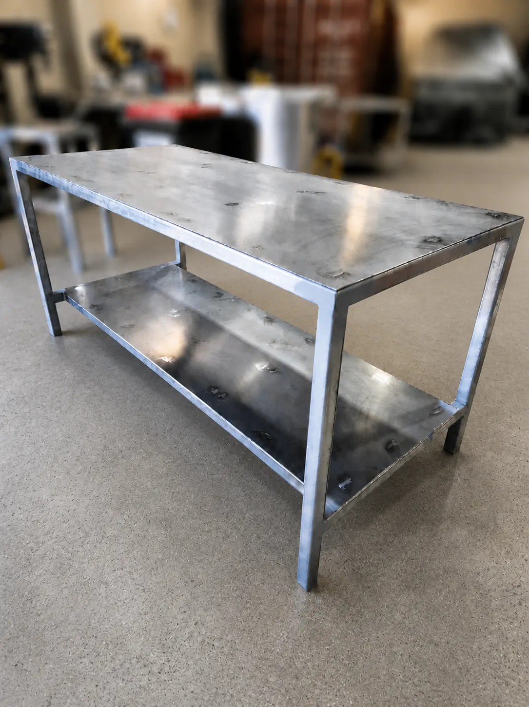 Long raw steel workbench with lower shelf